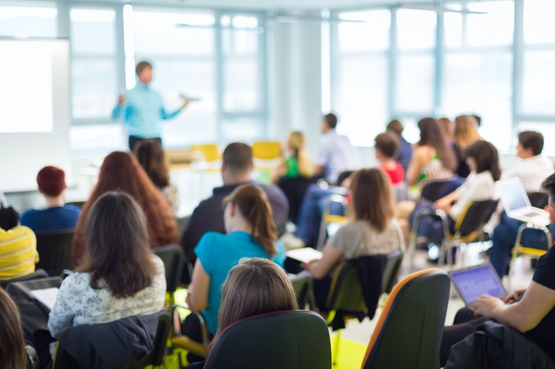 higher education students with hands up in class