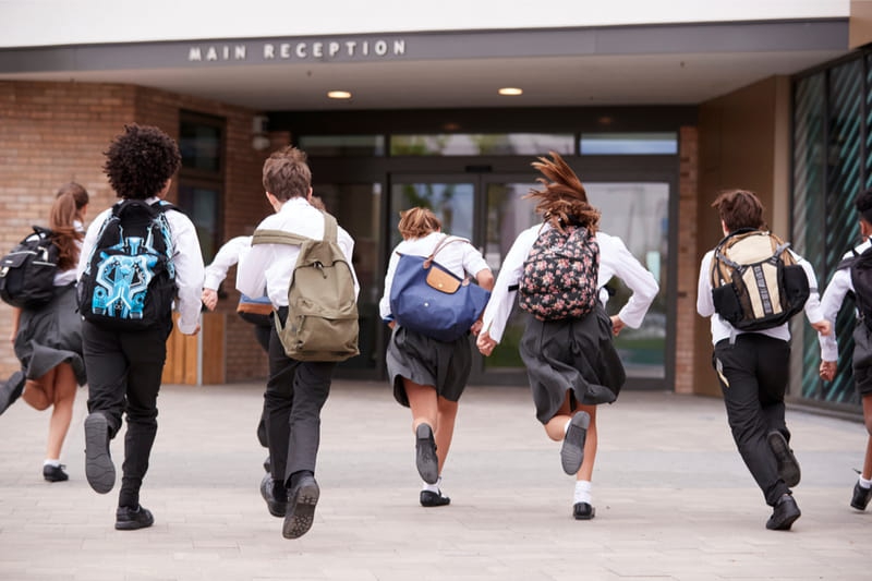 school children running towards school